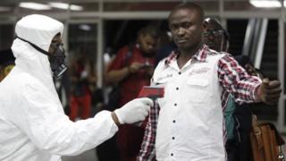 A Nigerian port health official uses a thermometer on a worker at the arrivals hall of Murtala Muhammed International Airport in Lagos, Nigeria, Wednesday, Aug. 6, 2014.
