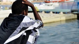 A young survivor of a shipwreck of migrants off immigrants off the Italian coast looks out over the water of Lampedusa on 8 October 2013