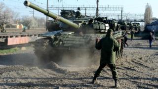 Russian soldiers unload T-72 tanks from a train near the Crimean capital Simferopol, on March 31, 2014
