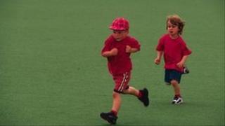 Two children running across playing field
