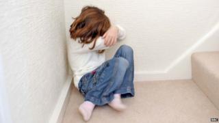 A young girl covers her face. File photo