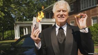 A wealthy man holds burning money.