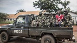 A local resident sits amid Congolese soldiers of the African-led International Support Mission to the Central African Republic (MISCA)