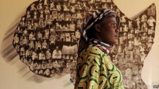An African refugee walks with her son on 17 June 2013 past a map of Africa at an exhibition hall in Rabat, Morocco