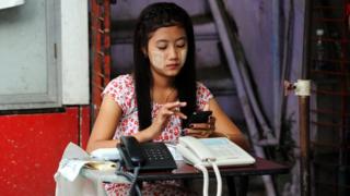 Woman in Myanmar with mobile and two landline phones