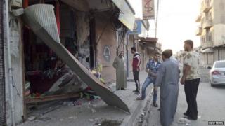 Men inspect damage to a shop after US air strikes in the Syrian city of Raqqa (23 September 2014)