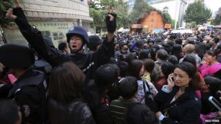 A police officer tries to maintain order outside a school gate after a stampede at a primary school, in Kunming, Yunnan province September 26, 2014
