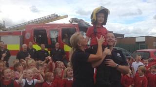 Liam Mansell is hoisted aloft by firefighters as fellow schoolchildren look on