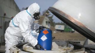 A Worker in protective clothing unloads a dummy grenade during a press day at the GEKA facility on 5 March 2014 in Munster, Germany.