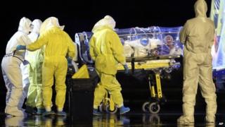 Aid workers and doctors transfer Manuel Garcia Viejo, a Spanish priest who was diagnosed with Ebola while working in Sierra Leone, from a military plane to an ambulance near Madrid, Spain, on 22 September 2014