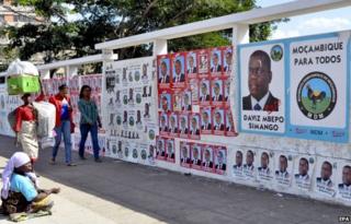 People walk pass a wall adorned with various election campaign posters in Maputo, Mozambique, 02 October 2014.