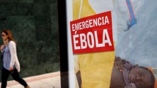 A woman walks past a bus stop banner reading "Emergency Ebola" near Madrid, Spain. Photo: 9 October 2014