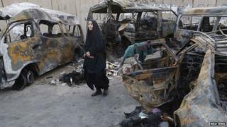 A woman looks at vehicles destroyed in a car bomb attack in the Shaoula neighbourhood of Baghdad October 12, 2014