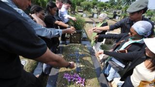 Indonesian journalists along with foreign colleagues sow flowers onto a tomb of five journalist as Australian Shirley Shackleton (C), widow of Australian journalist Greg Shackleton - killed in Balibo in what is now East Timor on 16 October 1975 - looks on at a cemetery in Jakarta on 14 October 2012