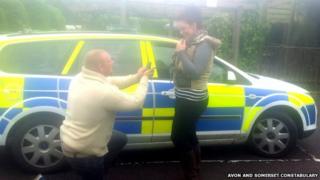 Caine Hutchings and Emily Dukeson in front of a police car