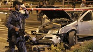 Israeli policeman stands near the car that hit pedestrians at Ammunition Hill light rail station in Jerusalem (22 October 2014)