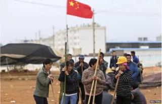 Villagers guard the entrance to Fuyou village next to the Chinese national flag in Jinning county, Kunming, Yunnan province 15 October 2014