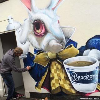 Graffiti artist painting March Hare mural