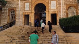 Students chat on the steps by the main entrance