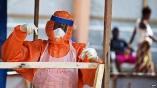 A health worker wearing a personal protective equipment works on 11 November 2014 outside Freetown