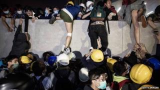 Pro-democracy protesters climb a wall as police officers disperse them outside the Legislative Council building after clashes with pro-democracy activists on 19 November 2014 in Hong Kong.