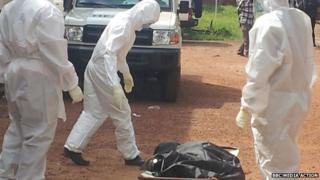 People look at a body outside hospital in Kenema