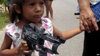 A Mexican girl holds a toy gun in south-western Guerrero state