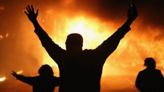 A protestor is silhouetted against a fire in Ferguson, Missouri.