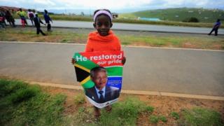 A young girl waits for the funeral cortege of former South African president Nelson Mandela as it passes through Qunu on its way to his family's rural home on 14 December 2013 in Qunu, South Africa