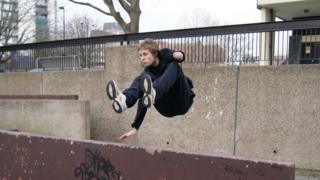James performing a parkour jump over a metal barrier