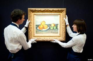 Sotheby's employees pose in front of 'Les Pommes' by Paul Cezanne