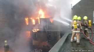 firefighters hosing flames