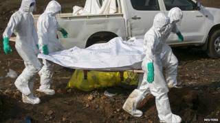 Health workers carry the body of a suspected Ebola victim for burial at a cemetery in Freetown December 21, 2014.