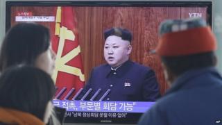 Passers-by at a Seoul train station watch Kim Jong-un's speech