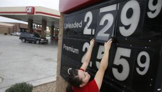 Quick Trip clerk Roxana Valverde adjusts the gas price sign numbers at a Tolleson, Ariz. QT convenience store as gas prices continue to tumble nationwide.