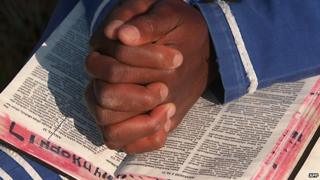 A South African praying with a Bible - archive shot