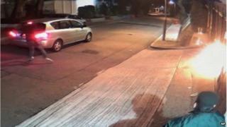 This screen capture taken from a surveillance video shows a car backing up to the gates of pro-democracy media magnate Jimmy Lai's home early Monday, 12 January 2015 and a masked attacker getting out to throw what looks to be a Molotov cocktail before driving off.