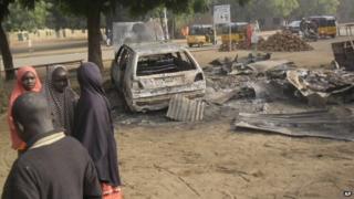 Children stand near the scene of a recent explosion in a mobile phone market in Potiskum, Nigeria, on 12 January 2015