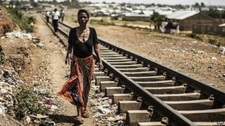 A woman walks next to train tracks in Zambia on 12 November 2014