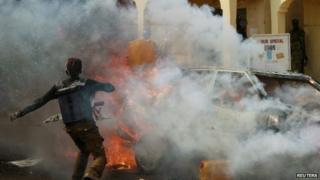 A man throws a container of water towards a burning car after a bomb explosion barely a few minutes after Nigerian President Goodluck Jonathan left Gombe stadium on 2 February 2015