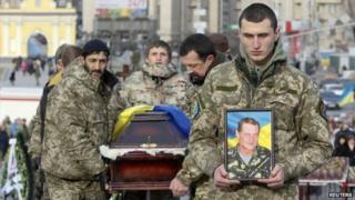 Ukrainian soldiers carry the coffin bearing the body a member of self-defence battalion "Aydar" during a funeral ceremony at Independence Square in central Kiev