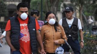 People walk with face masks due to ashes from the Fuego volcano in Antigua Guatemala, Sacatepequez departamento, 45 km southwest of Guatemala City on Febrary 7, 2015.