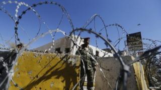 A soldier stands guard behind a roadblock in the Yemeni capital Sanaa