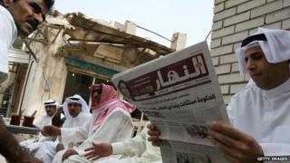 A Kuwaiti man reads a local newspaper amongst friends