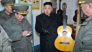 North Korean leader Kim Jong-Un (C) holds a guitar during his visit to a military unit on the Wolnae Islet Defence Detachment in the western sector of the front line, which is near Baengnyeong Island of South Korea 12 March 2013.