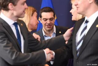 Greek Prime Minister Alexis Tsipras (centre) speaks with fellow delegates during a family photo at an European Council leaders summit in Brussels on 12 February 2015