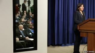 With meeting participants reflected in a mirror, Paris Mayor Anne Hidalgo (R) delivers remarks during the White House Summit on Countering Violent Extremism