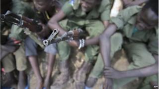 Child soldiers sit with their rifles at a ceremony of the child soldiers disarmament, demobilisation and reintegration in Pibor overseen by UNICEF and partners on 10 February 2015