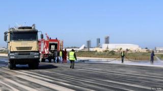 Fire brigade workers clean the runway after an airstrike hit Tripoli's Maitiga airport 3 March, 2015