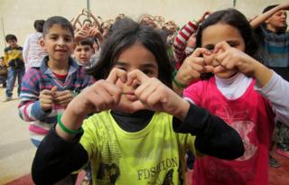Children making heart signs instead of V for Victory signs
